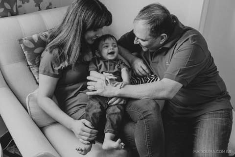 Fotografia de pais sentado na sala segurando bebê'