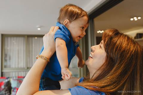 Fotografia de criança sorrindo no colo da mãe'