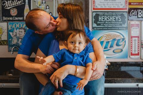 Fotografia de mãe beijando o pai enquanto segura o bebê'
