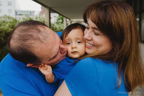 Fotografia de pai beijando criança no colo da mãe'