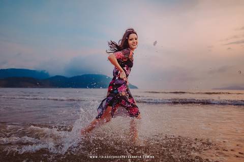 ensaio externo em santos, 15 anos, praia, por do sol, nuvens, vestido florido, mar, beira de água, correndo'