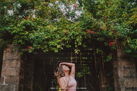 Foto de mulher centralizada no tunel do Orquidario com a parte de cima bastante florida , com cabelos ao vento'