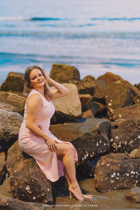 Sentada nas pedrad da ponta da praia em santos'