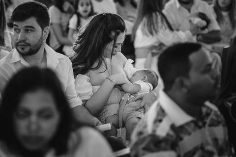 Mamãe amamentando o filho durante o Batismo do filho na Igreja Matriz em São Gotardo.'