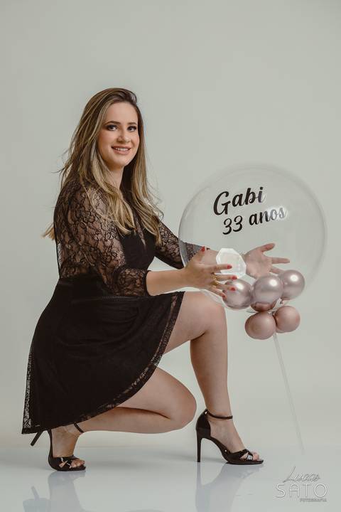 Ensaio feminino de aniversário com acessório de balão personalizado. Vestido preto para ensaio em estúdio.'