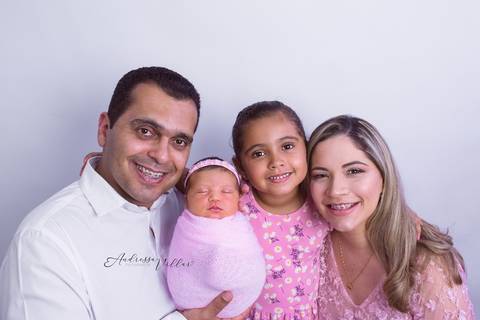 Da esquerda para direita os rostos enfileirados do pai, filha recem nascida, filha mais velha e mãe. todos sorrindo. '