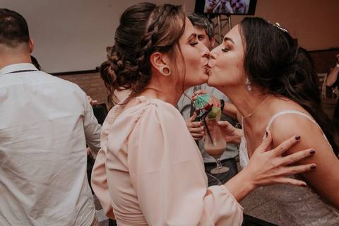 festa de casamento convidados curtindo madrinha dando um beijo na boca da noiva '