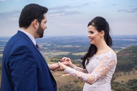 noiva colocando aliança no noivo em casamento ao ar livre'