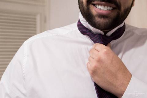 noivo colocando gravata e terno no dia do casamento'