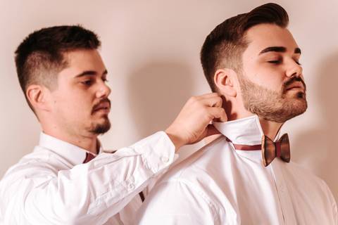 Noivo colocando a gravata de madeira que usou no dia do casamento'