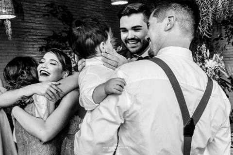 Noivos abraçam padrinho e cumprimentam daminhas'