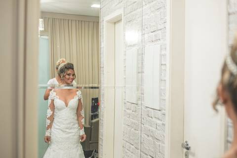 Noiva (Denise) sorrindo em frente ao espelho.'