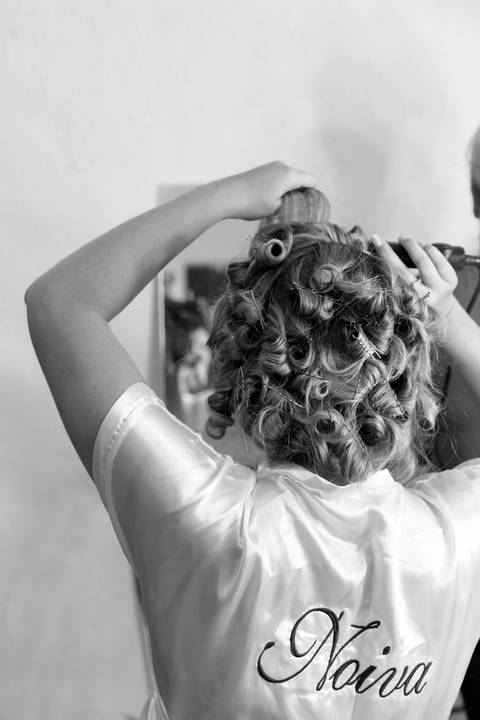 Noiva de roupão arrumando o cabelo no making of'