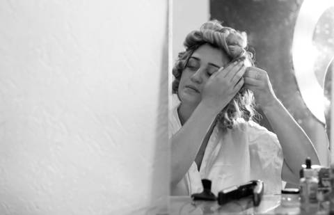 Noiva no espelho arrumando o cabelo no making of'