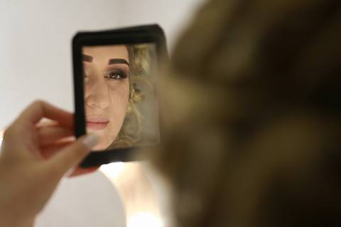 noiva se olhando no espelho durante o making of'