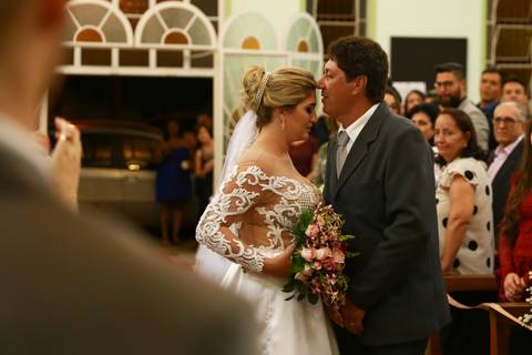 Pai beija testa da noiva ao entrega-la ao noivo que espera ansioso no altar da Igreja Cristo Bom Pastor'