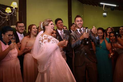 Noivo estoura champagne, no momento do brinde, com todos os padrinhos e madrinhas reunidos na pista de dança'