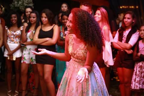 aniversariante recebe surpresa, na pista de dança, foto de meio corpo mostra menina surpresa com ao receber a noticía'