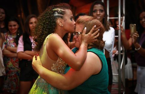 aniversariante beija testa da avó, emocionada, após receber anel de presente, na pista de dança'