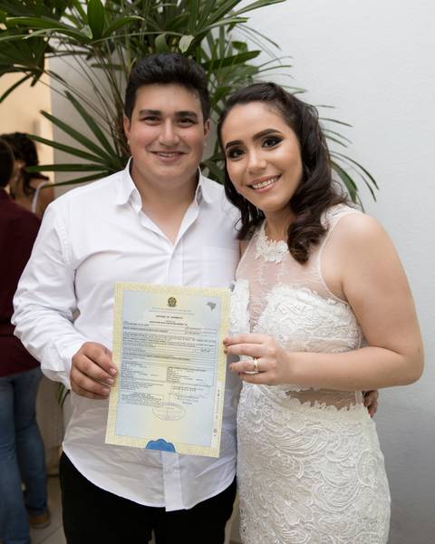 noivos posam na saída do cartório com certidão'