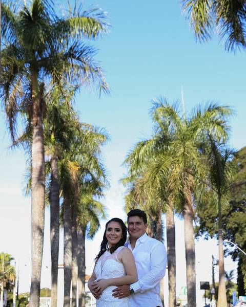 Noivos posam abraçados no Parque de Exposições Fernando Costa - Uberaba - MG. Em frente aos  coqueiros'