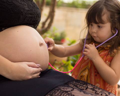 Irmã mais velha escuta irmã mais nova na barriga da mãe'