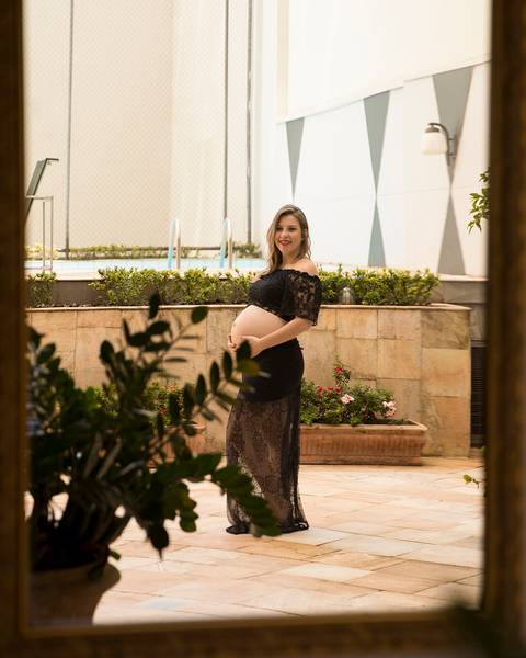 Gestante posa para foto tirada através do espelho.'
