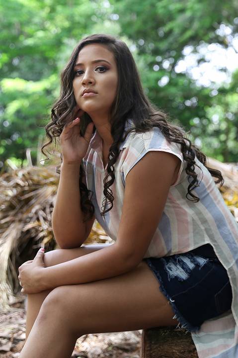 Debutante posa sentada na pilha de troncos secos'