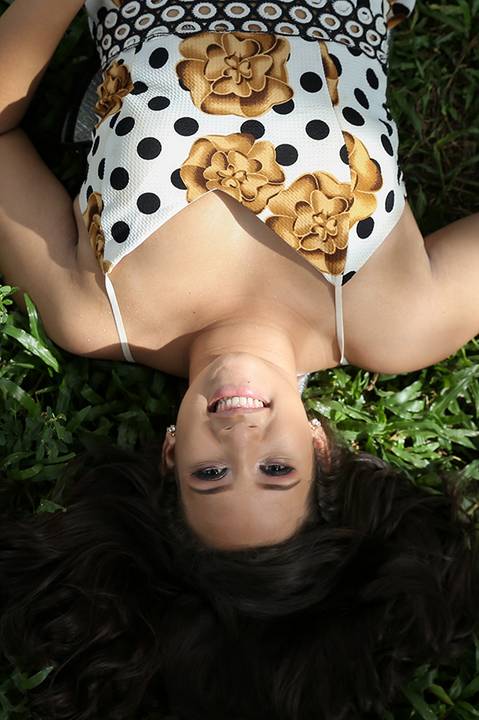 Debutante olha para câmera, deitada de costas na grama'