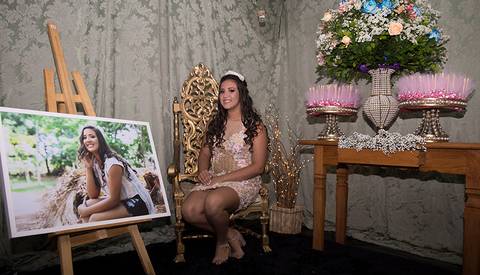 Debutante posa na decoração, entre lembrancinhas e quadro'