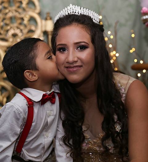 Irmão mais novo da debutante, beija irmã no rosto para foto'