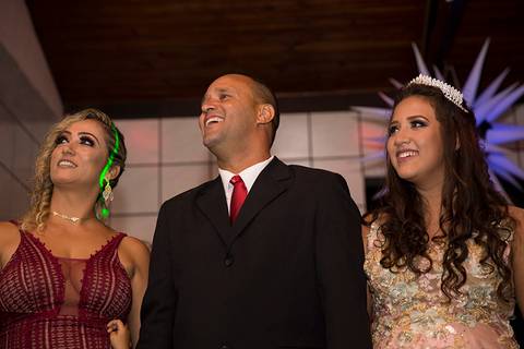 Debutante e pais observam homenagem no telão'