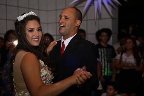 Debutante dança valsa com seu pai, ambos sorriem'