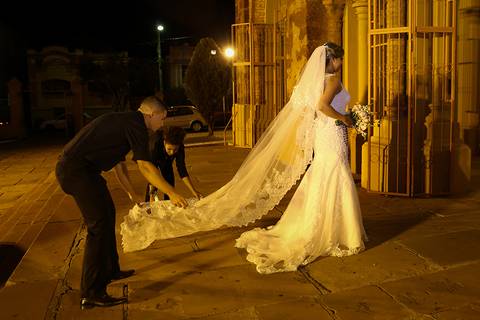 Equipe de cerimonialistas arrumam véu da noiva, momentos antes da sua entrada na igreja'