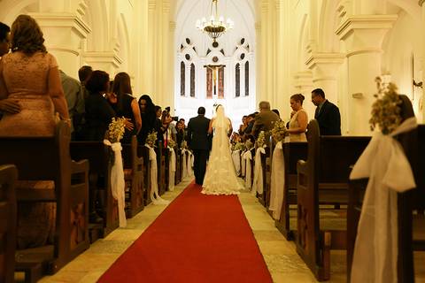 Noiva e seu pai entram na igreja, de costas pode se notar o belo véu da noiva'