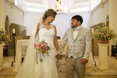 Noivos, felizes no altar, após o beijo, de olham e sorriem'