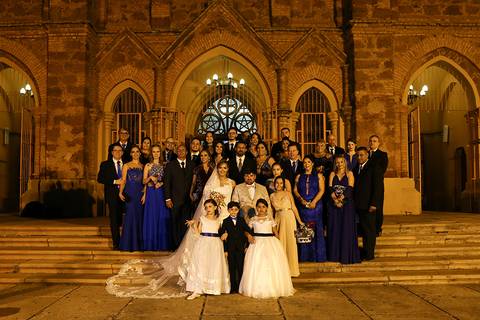 Noivos, damas, pagem, pais da noiva e todos padrinhos posam nos degrais da igreja São Domingos'