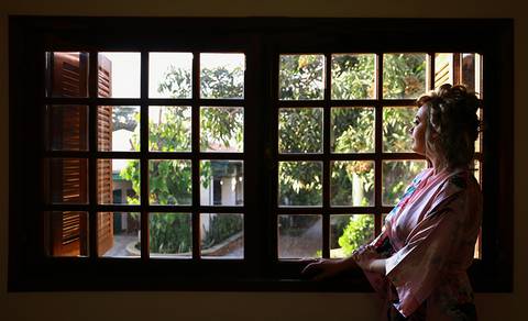 Noiva, durante making of, olha pela janela, ansiosa pelo grande momento'