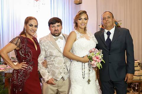 Noivos posam com os pais da noiva da mesa do bolo'