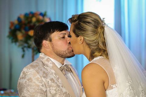 Noivos se beijam na mesa do bolo'