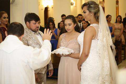 Padre recebe e abençoa as alianças, nas mãos da dama de honra'