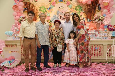 Aniversariante posa com a família de seu pai na mesa do bolo'