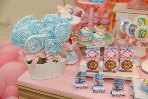 Detalhes na mesa do bolo, pirulitos, caixinhas e doces em forma de livro, tudo em tema Alice no País das Maravilhas'