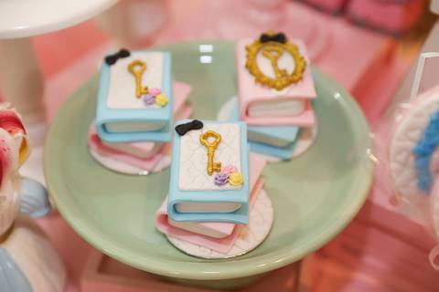 Detalhes na mesa do bolo,  doces em forma de livro com detalhes de chave, tudo em tema Alice no País '