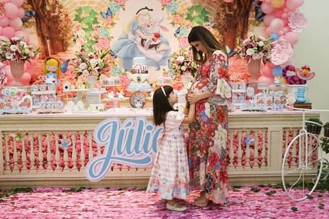 Aniversariante acaricia barriga da mãe gestante, na mesa do bolo'