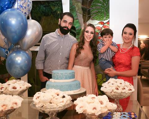 Aniversariante posa com os tios e o priminho, na mesa do bolo'