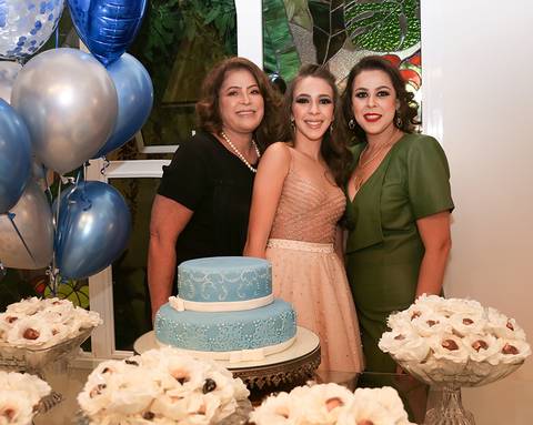 Aniversariante posa com a mãe e a avó, na mesa do bolo'