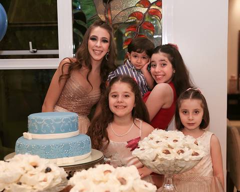 Aniversariante posa com os primos, na mesa do bolo'
