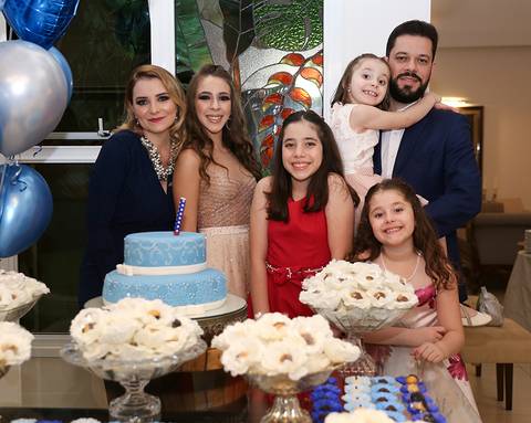 Aniversariante posa com os tios e as primas, na mesa do bolo'