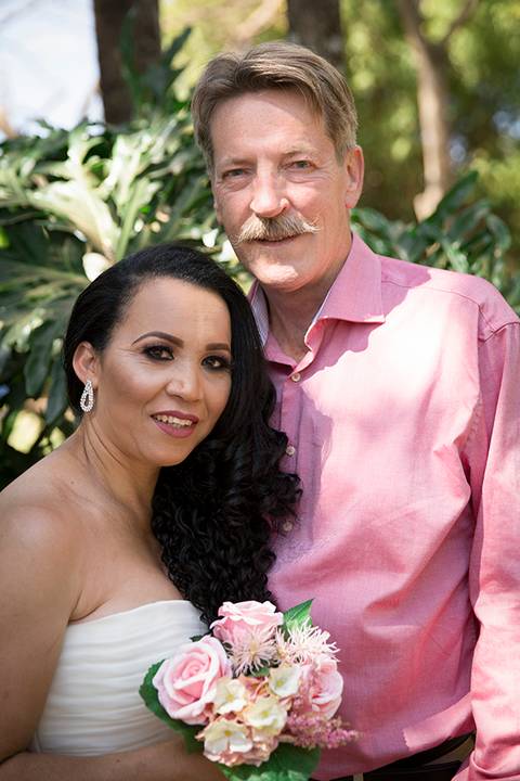 Retrato dos noivos em meio corpo. Ambos olham diretamente para câmera'